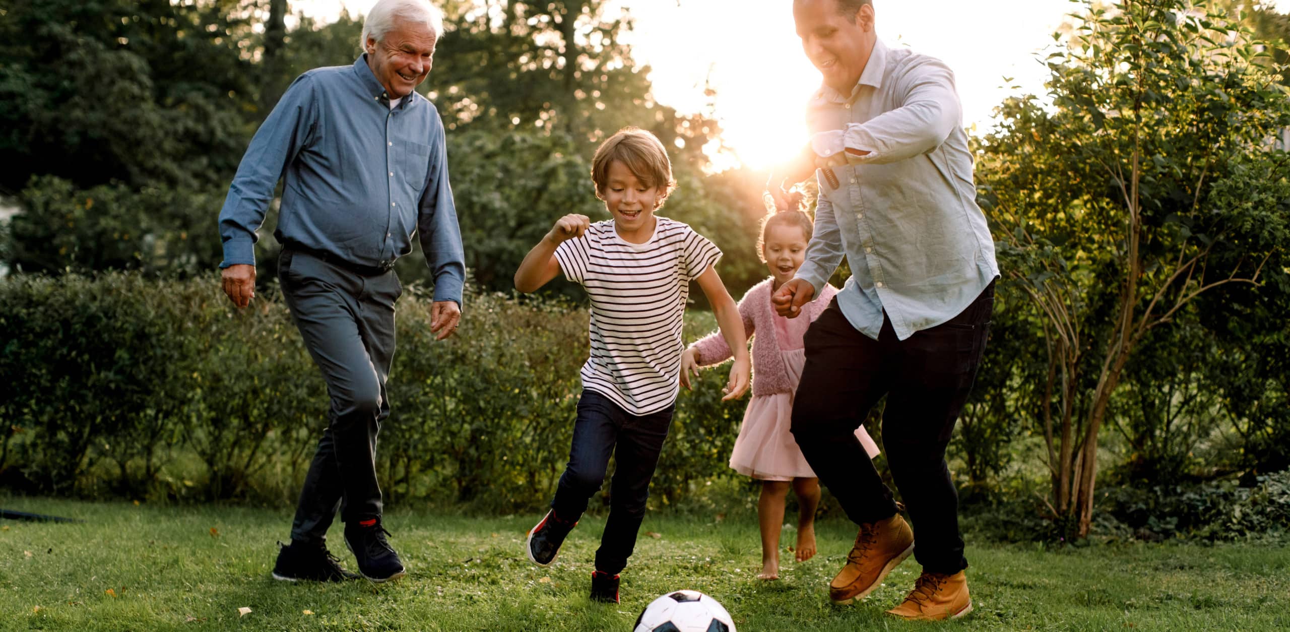 Full length of multi-generation family playing soccer in backyard. Foto: Maskot